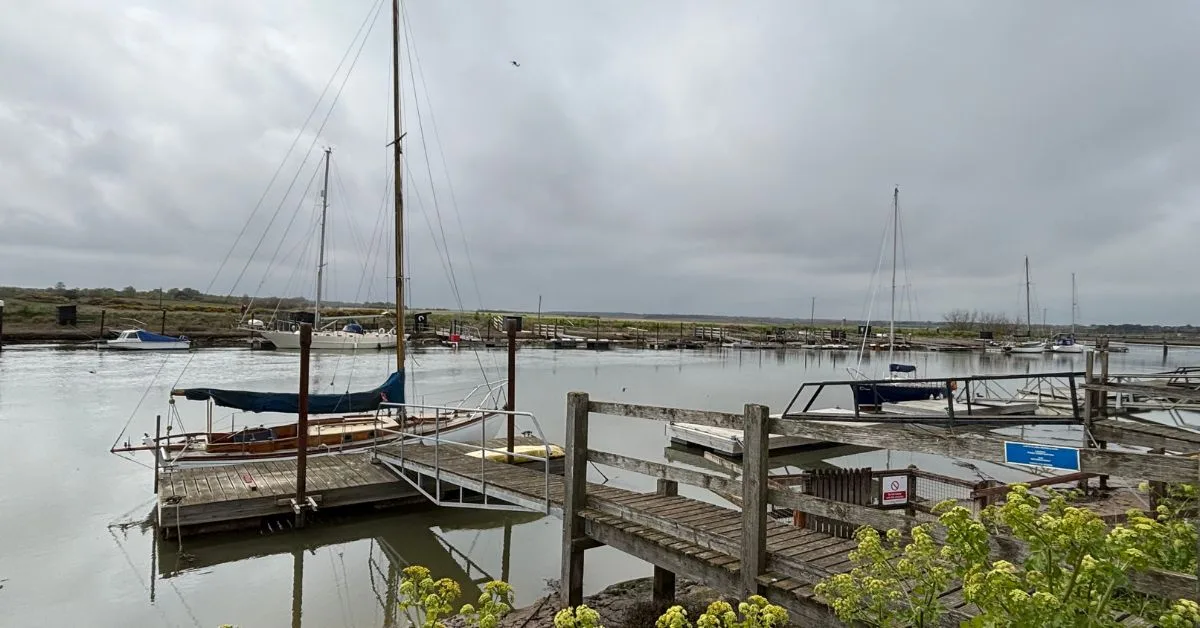 Small boats moored up to wooden boardwalks on the river Blyth in Walberswick.