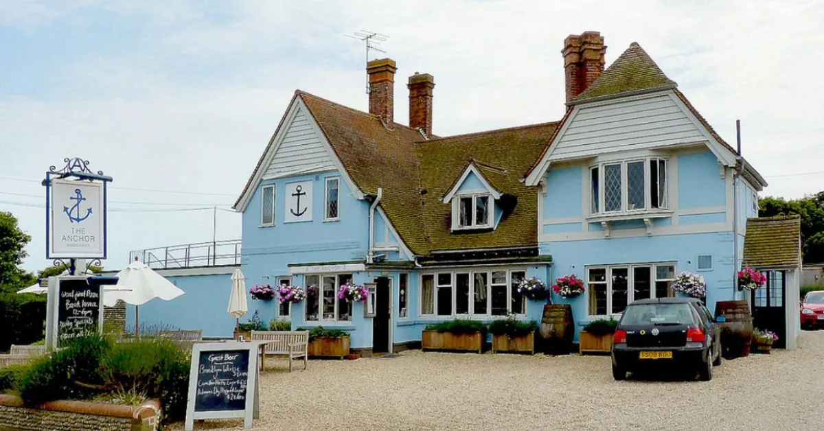 Outside of the Anchor pub with blue frontage and brick and flower hanging baskets.