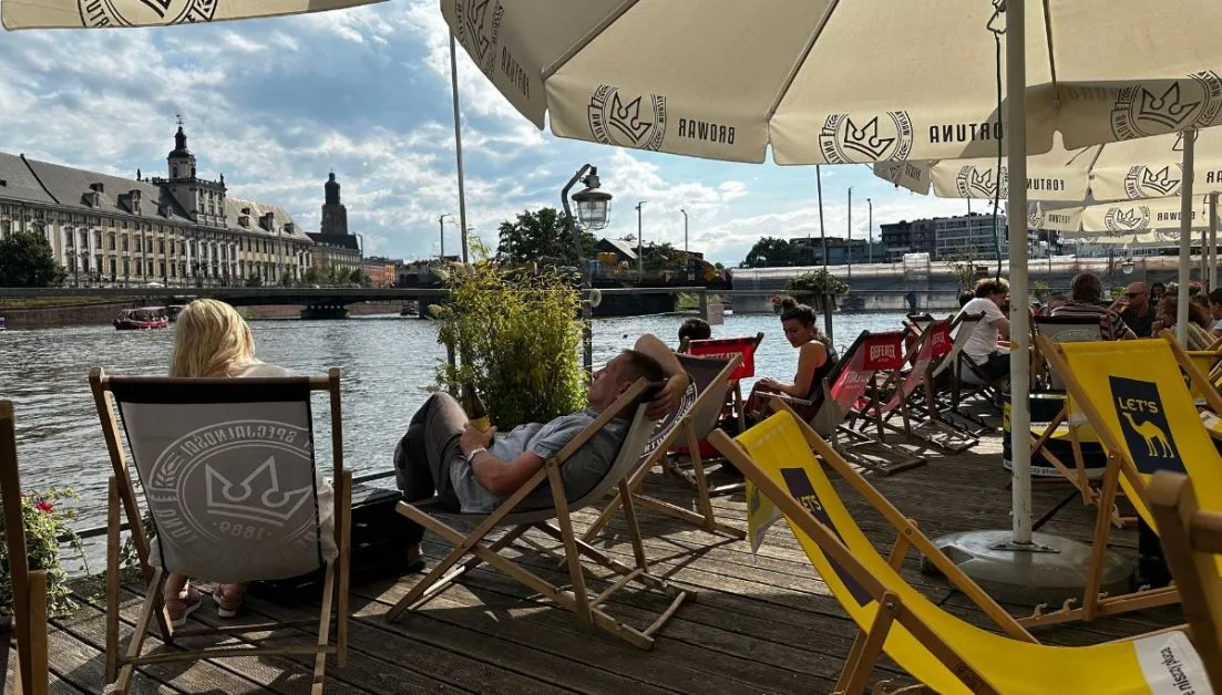 People are relaxing on deck chairs on the 'beach' riverside in Wroclaw.