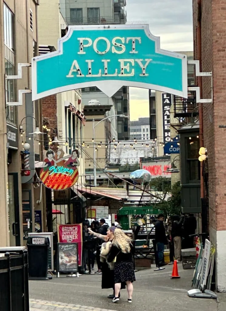 A blue and white sign for Post Alley, a street in central Seattle with many restaurants and bars.