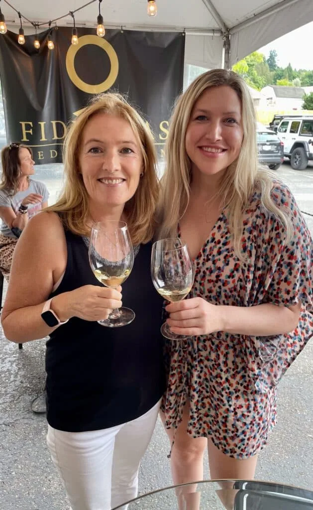 Two woman holding glasses of wine at a tasting room in Seattle.