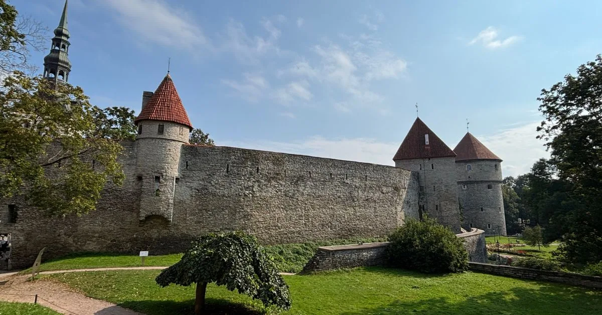 city walls showing three stone towers with red turrets.