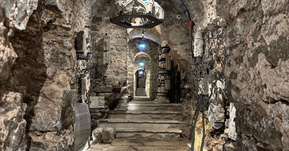 Underground stone walls and pathway with carved monuments and artefacts along the walkway
