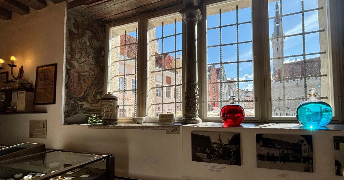 Inside the pharmacy with bottles of old fashioned medicine and other artefacts on display -open view onto old square from inside