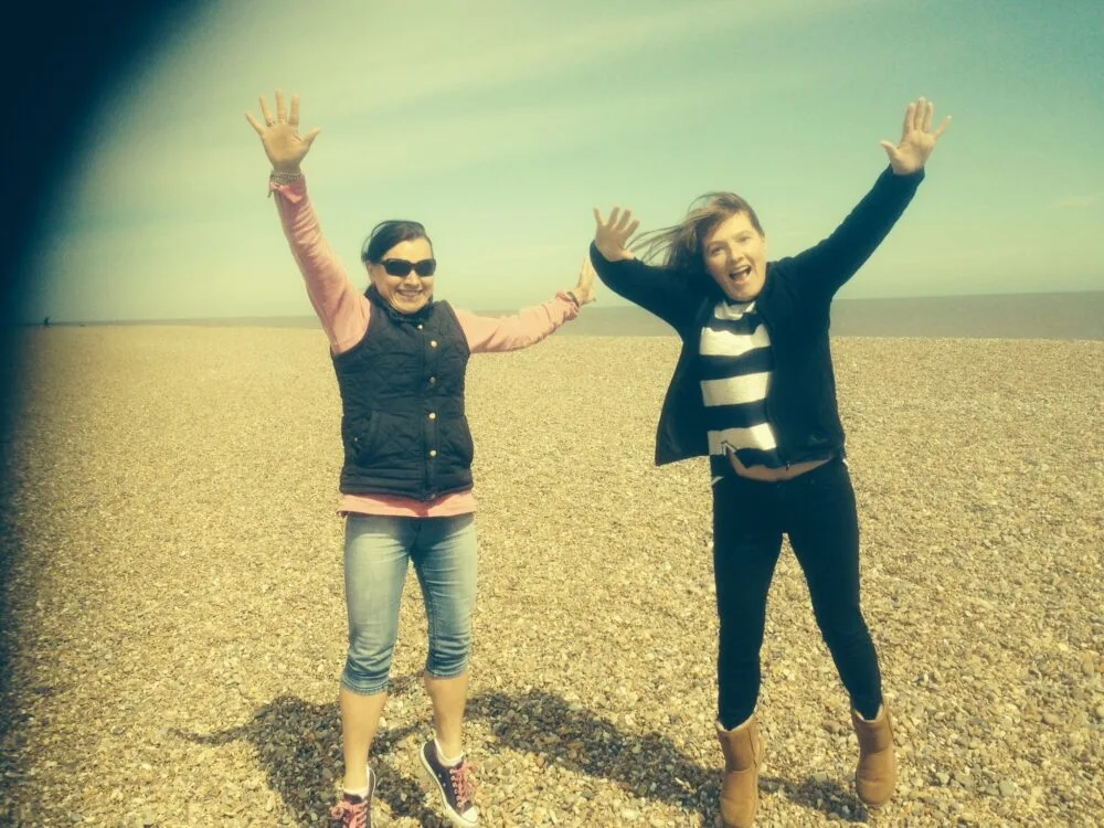 Two women jumping for fun on a beach.