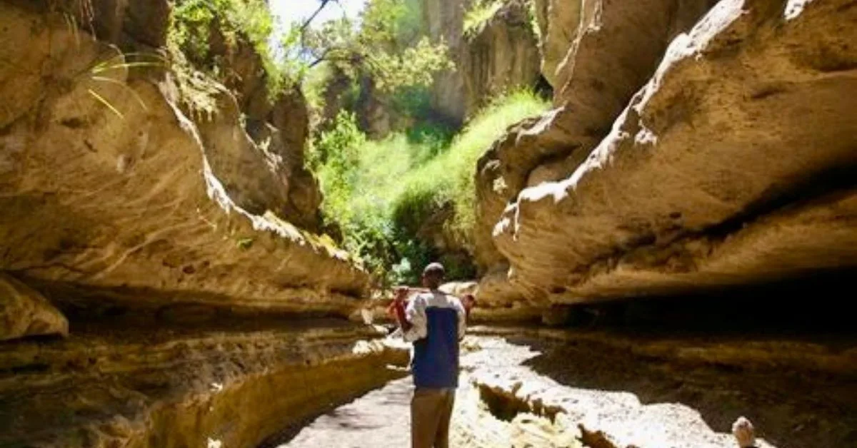 A person stands between stone that has been carved out by weather.