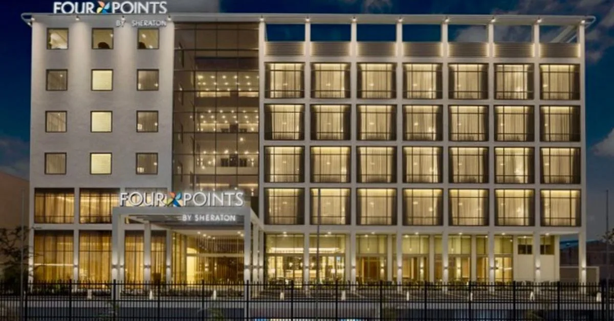 A hotel building lit up at night with Four Points Sheraton logo above entry way.
