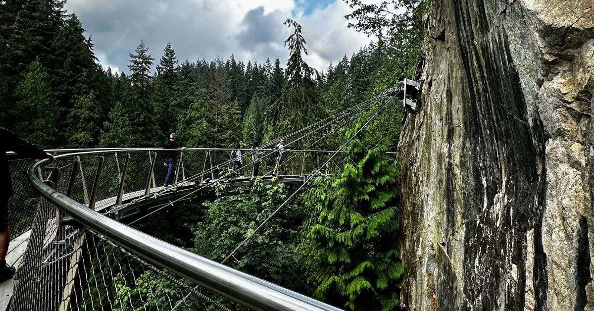 A curved suspended walkway attached to a cliff side.