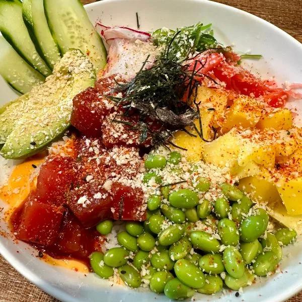 An asian salad dish featuring tuna, avocado, endamame and a selection of fresh vegetables.