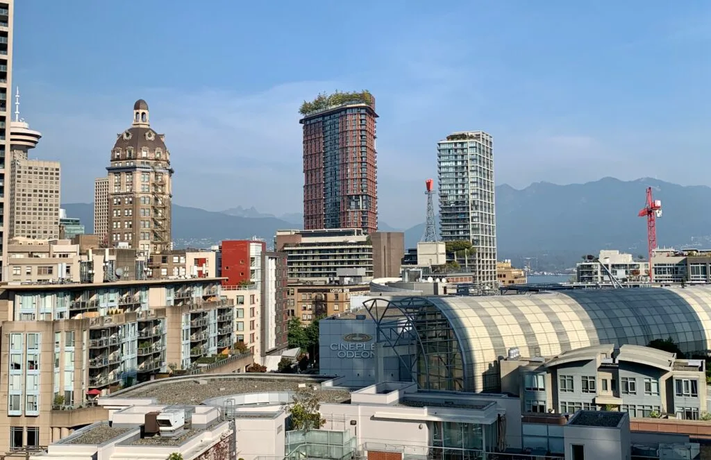 View of central Vancouver with high rise buildings and behind them mountains.