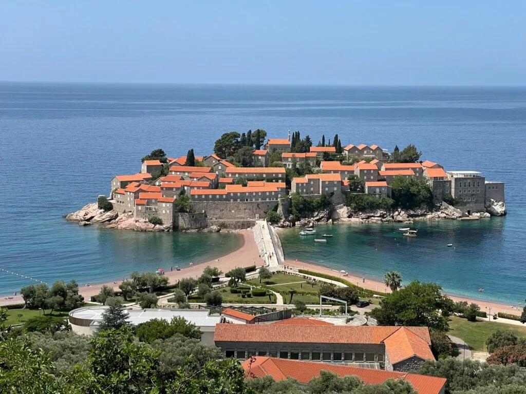 A man made island off Montenegro which is a private resort. Red tiled roofs and a causeway can be seen from the mainland.