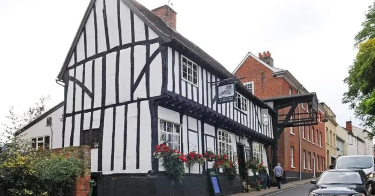 A black and white Tudor timber building in Woodbridge which is an Inn today. Flowers boxes hang from windows.
