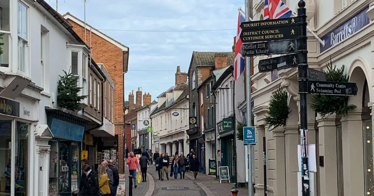 People are walking in a pedestrian area of Woodbridge enjoying shopping a range of different stores.
