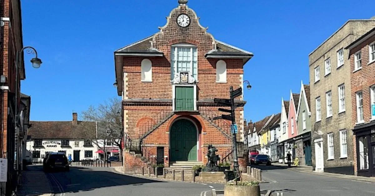 A double stair case leads up to the green door of Shire Hall in Woodbridge. A clock is fitted to the rounded ornate roof front decor.