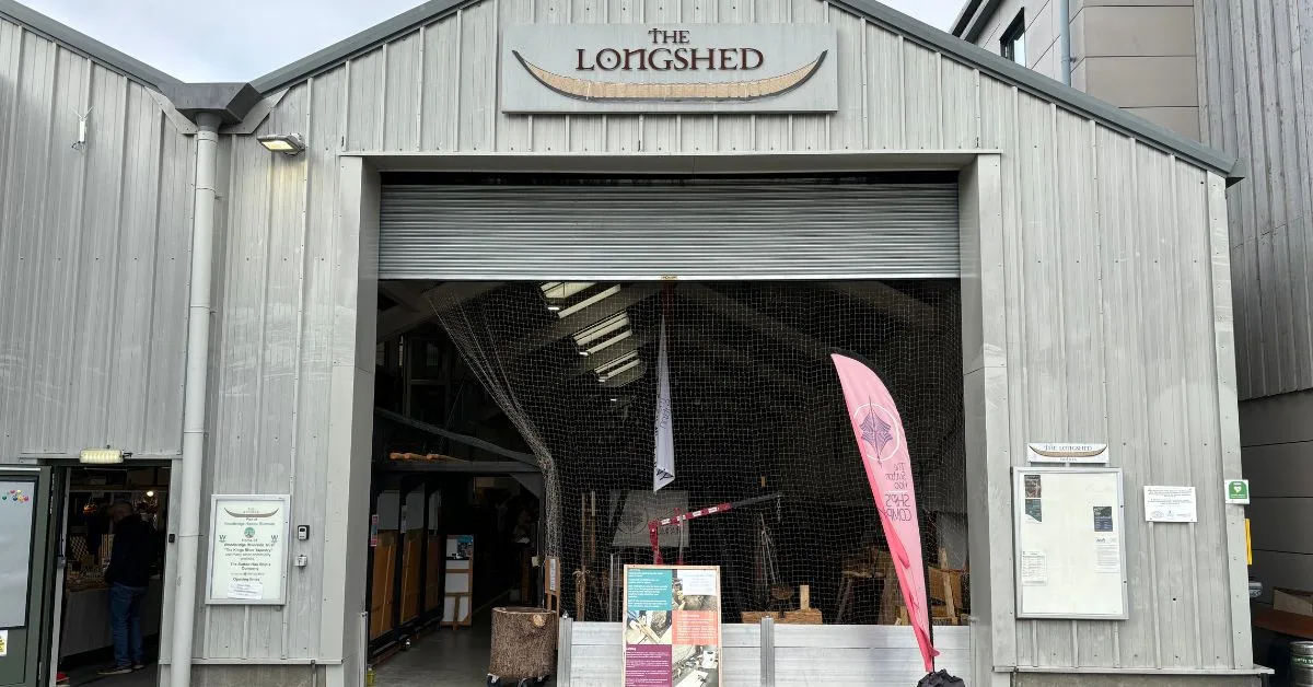 A sign “The Longshed” alerts visitors to a community shed  built from meta where volunteers work on projects such as rebuilding traditional boats.