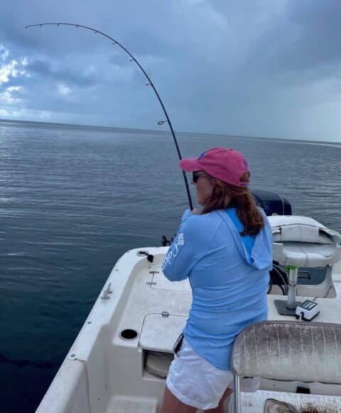 Woman has a catch on the line fishing off a boat in the shallow waters off Crystal River Coast, Florida.