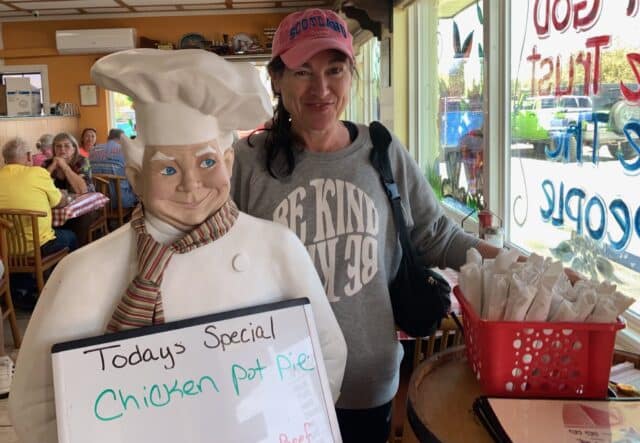 tourists stands next to a menu board in a breakfast cafe in Crystal River.
