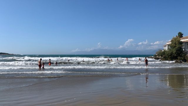 A wide beach with white cap waves crashing on the sands.