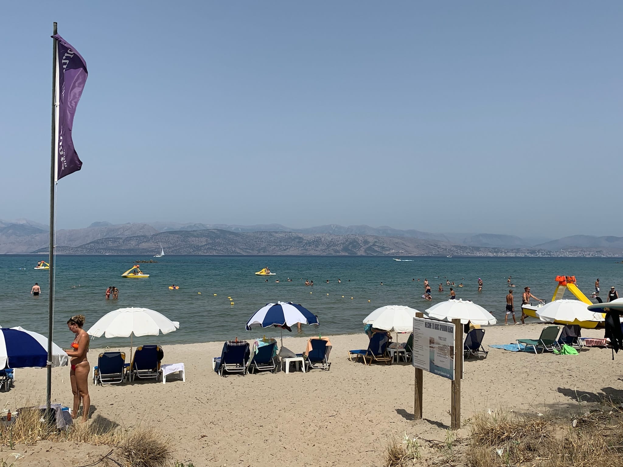 A beach with umbrellas and people sunbathing.