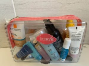 A plastic container showing toiletries as part of hand luggage post. The bag is clear plastic with an orange zipper.