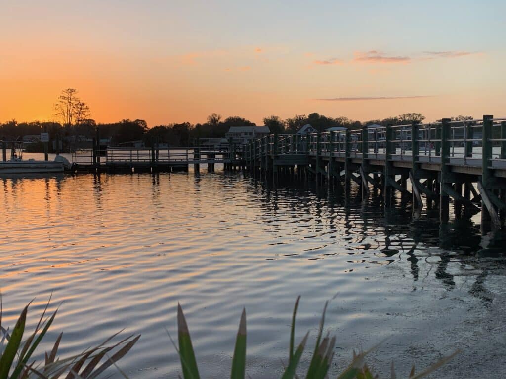 Sunrise over the marina and jetty in Crystal River Florida. Light orange hues fill the sky and reflect on the calm waters.