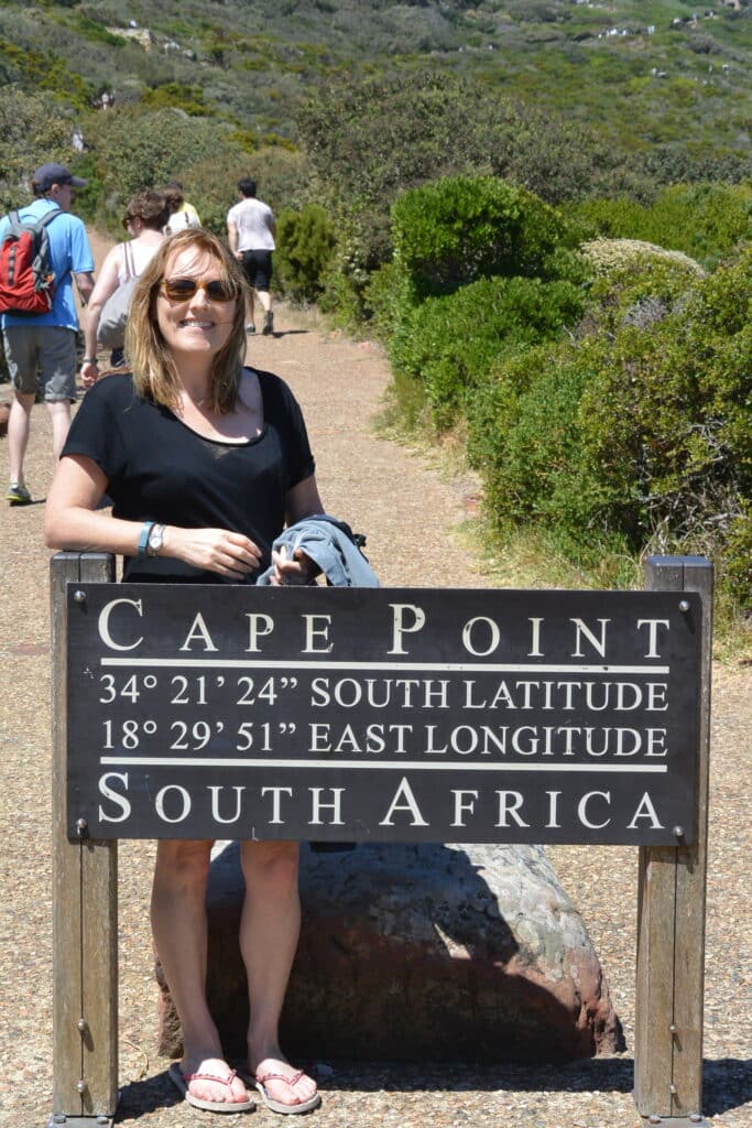 Cape Point sign Post and woman standing next to the latitude and longitude data.