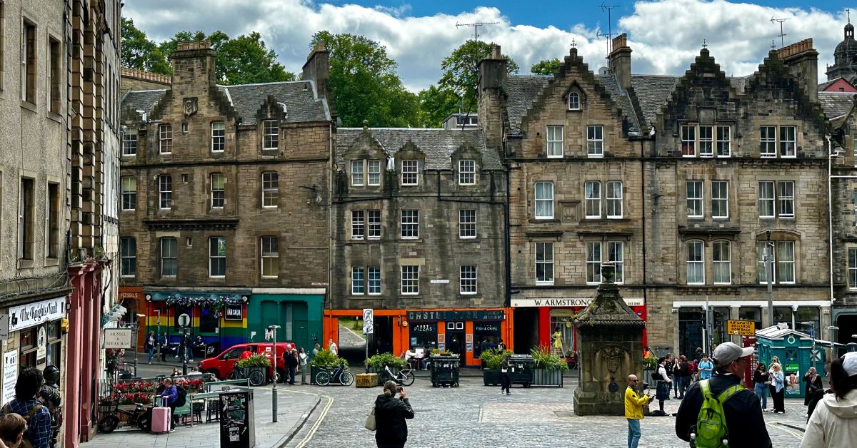 People exploring an old cobbled market area called Grassmarket in Edinburgh.