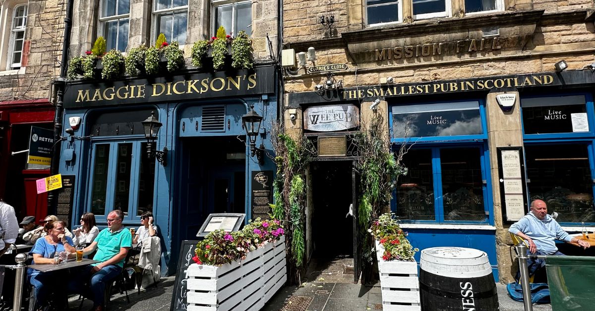 People sitting outside traditional pubs in The Grassmarket Edinburgh.