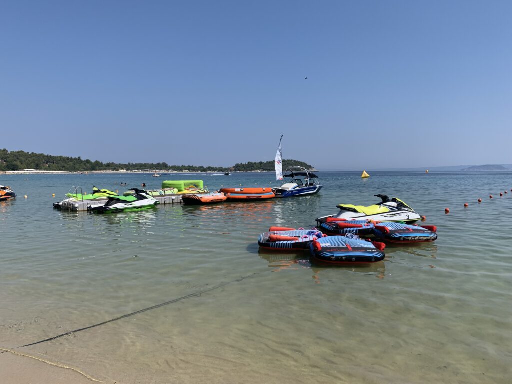 Very shallow water which is transparent. Around 10 small boats for tourists sit waiting for customers.