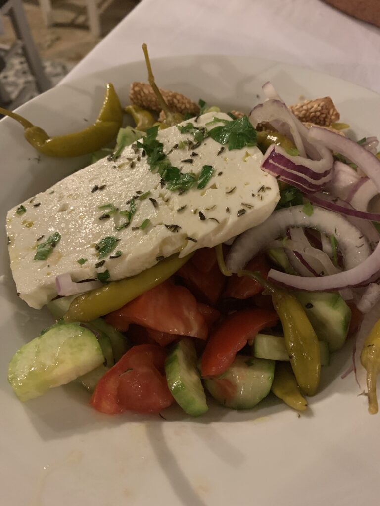a greek salad with feta cheese, tomatoes, olives and onion.