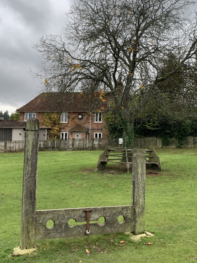 Old wooden stocks on a village green in England, UK.