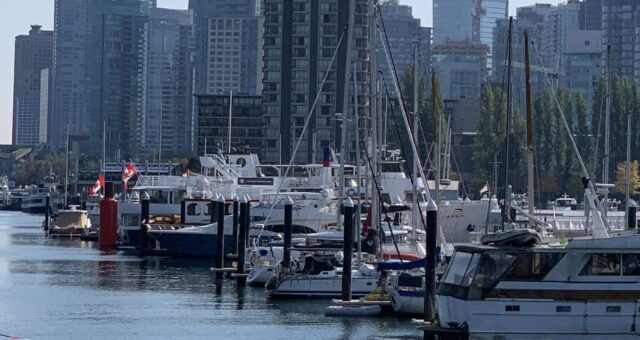 Vancouver Waterfront shows boats moored in front of high rise buildings on the waterfront. This is a popular area to explore during a weekend in Vancouver, Canada.