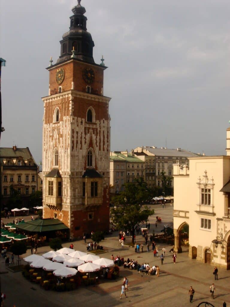 A church tower dominates this square in Krakow. Small market tents with white covers can be seen in the square below.
