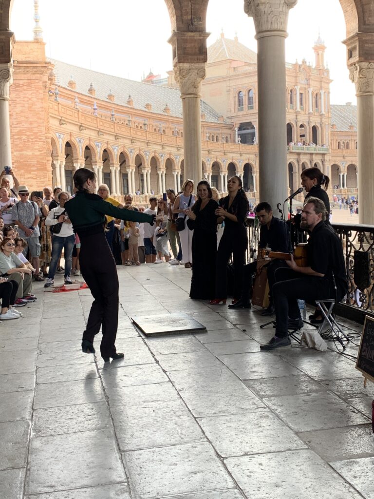 A man is playing guitar in Seville and others dance traditional flamenco dances.