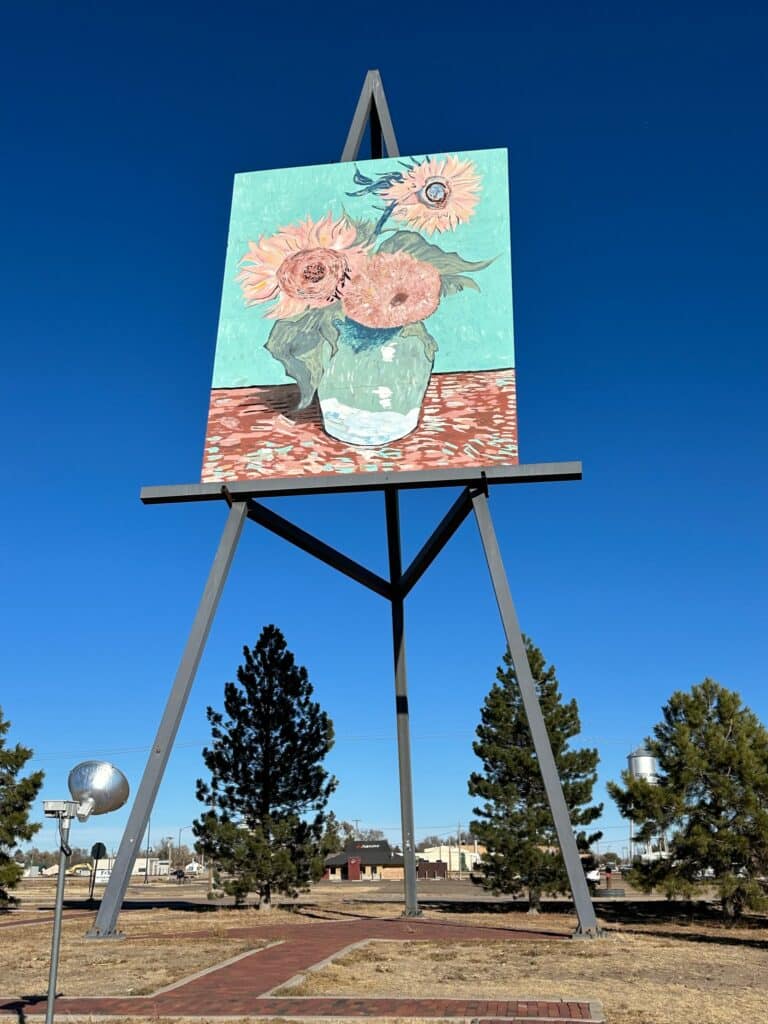 A giant easel with a sunflower painting is a popular stop off when on a roadtrip from Florida to Colorado via Kansas. The easel rises above fir trees and water towers.