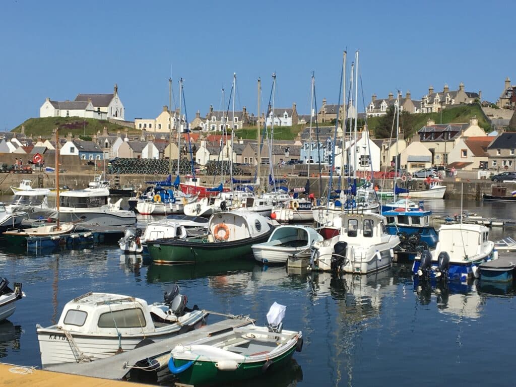 A fishing village in Moray Scotland with boats tied up in the stone wall harbour.