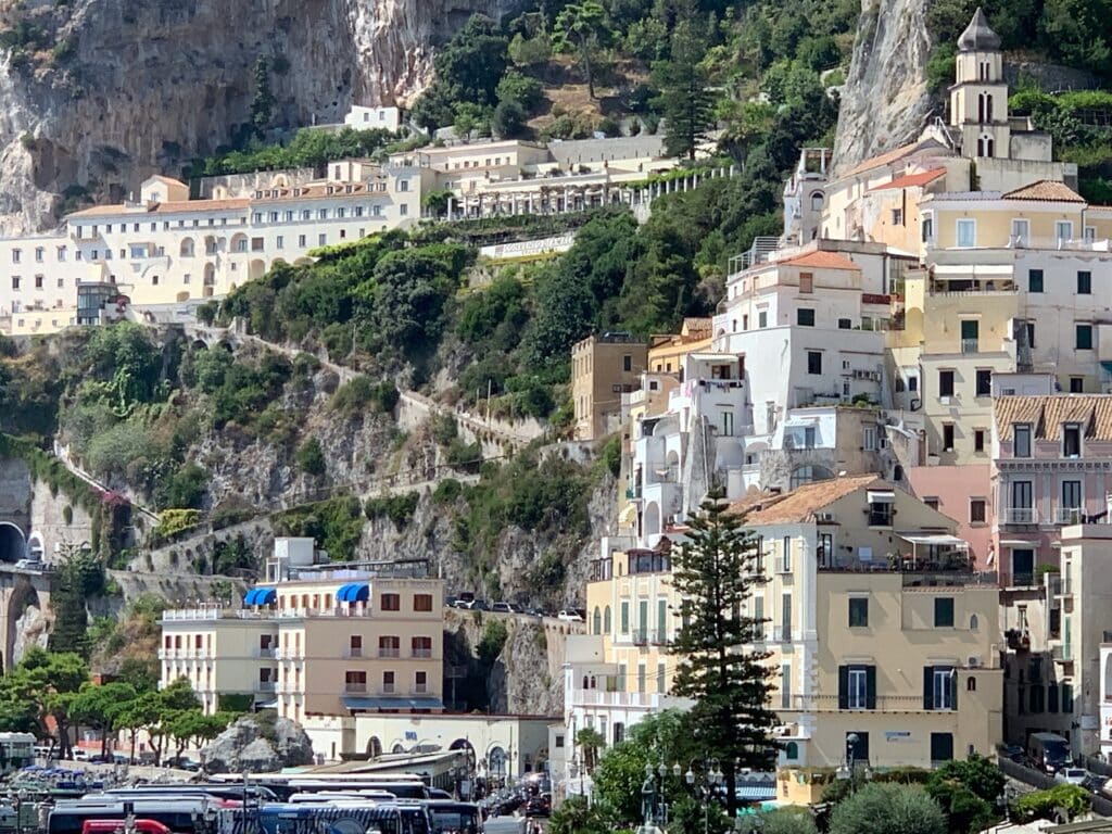 A village that clings to the cliffs of Amalfi Coast Italy with levels of homes and a steep winding street down to the water.
