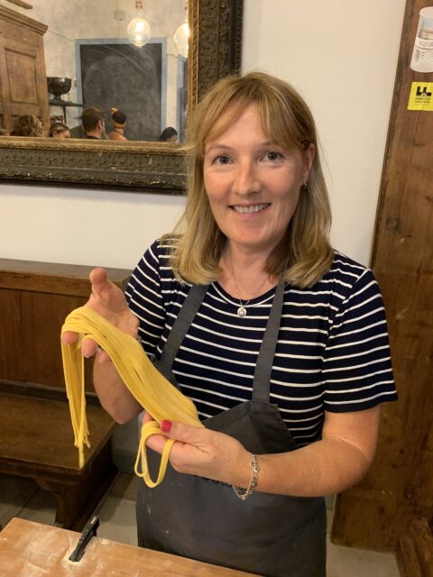Woman making pasta in Florence Italy with strings of spaghetti.