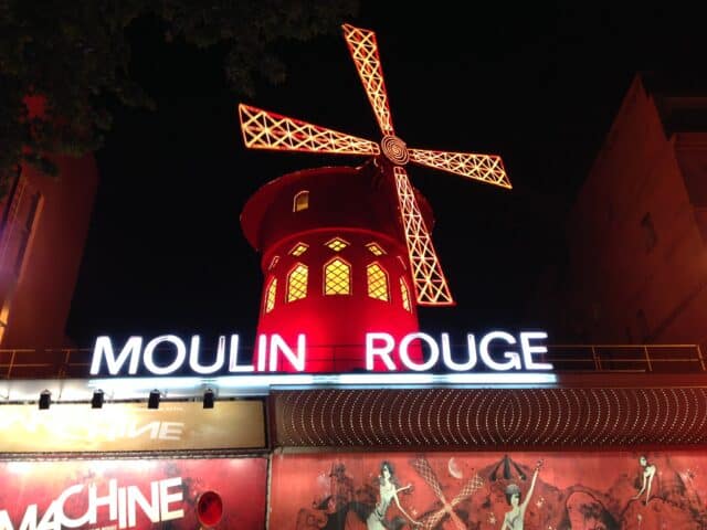 A red round building with the signage for Moulin Rouge and the distinctive windmill on top of the building.