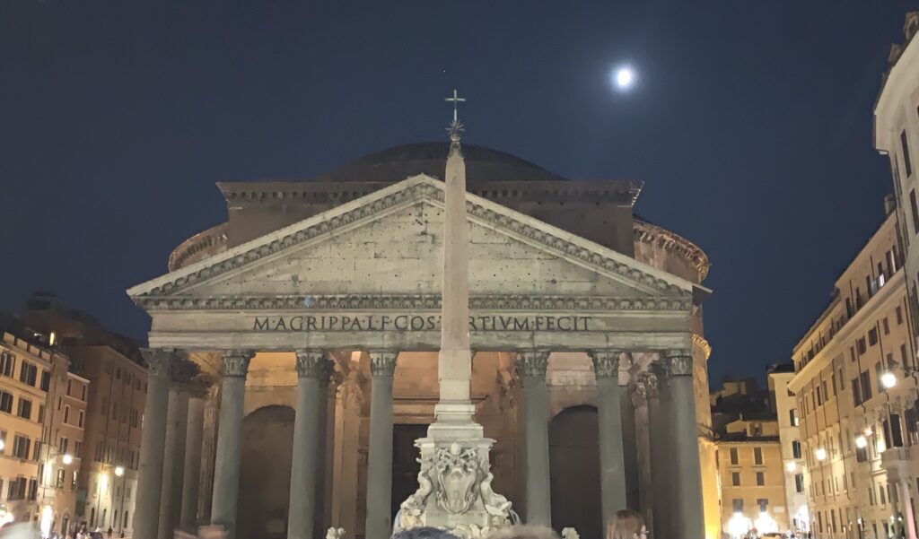 Night time dark sky with illuminated Pantheon in Rome City. Large columns showcase the main entrance of the church.