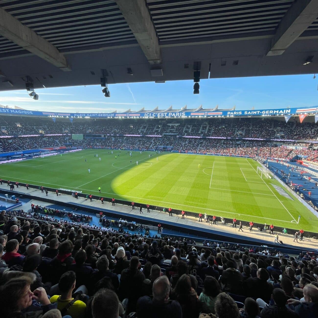 A football stadium with fans filling the stands and green field waiting for players.