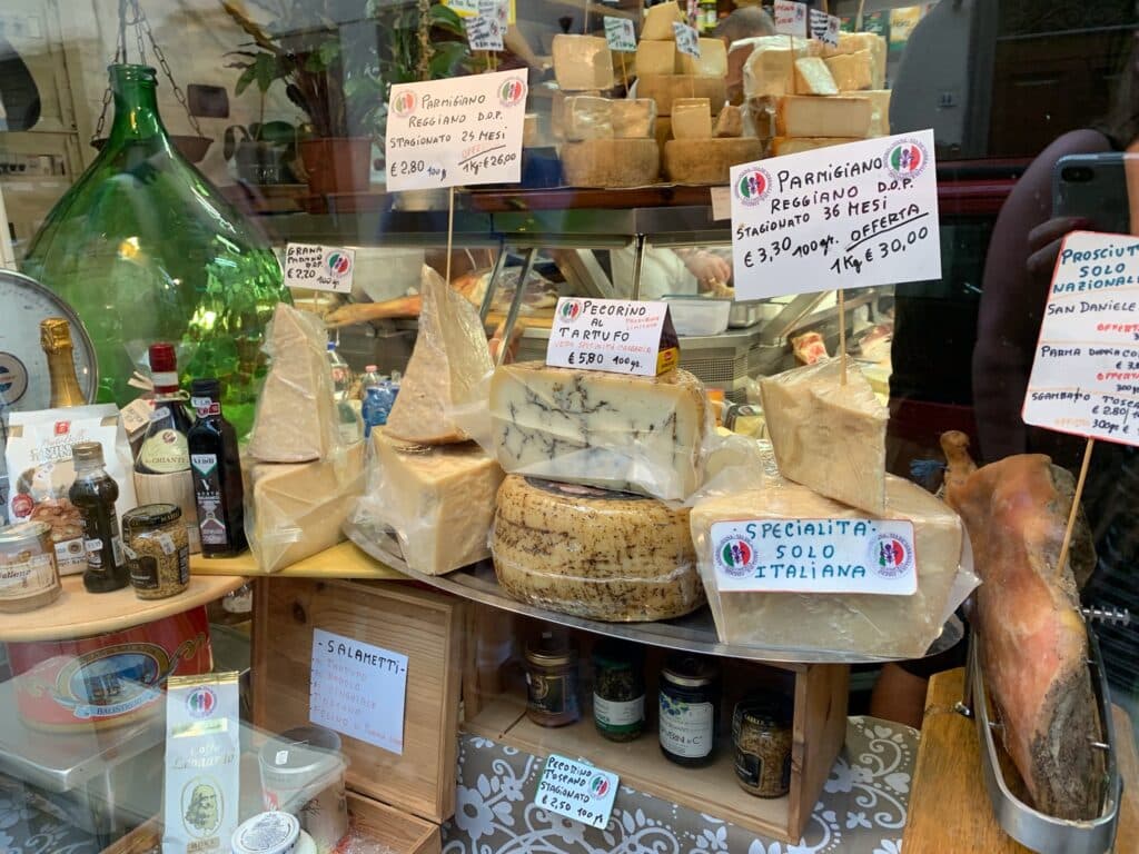 A selection of large cheese fill a counter in a cheese store.