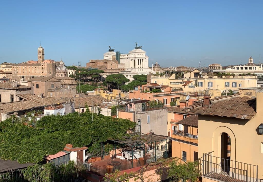 A view of Rome Italy with rooftops and ancient statues and moments soaring against the skyline.