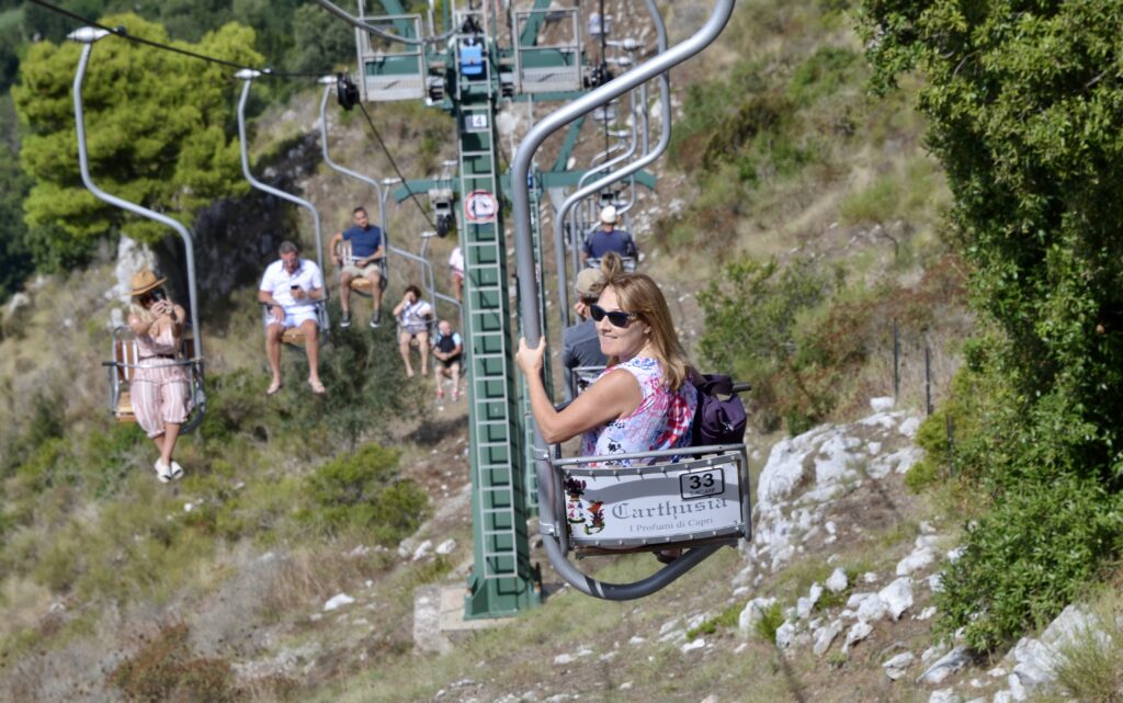 People are riding up the main hill in a chair cable system on the island of Capri.
