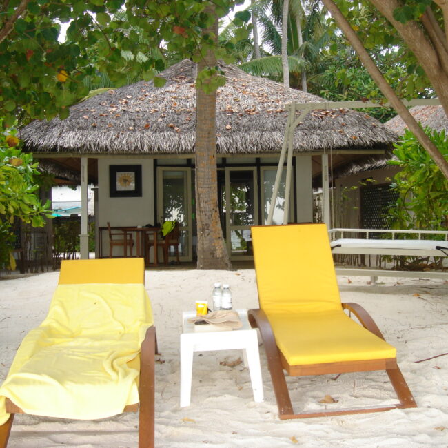 Two yellow sun loungers outside a beach bungalow on the Madives. This is another one of our dreamy destinations for romantic getaways.
