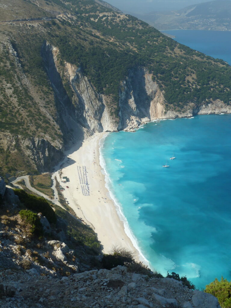 A secluded beach in Greece with strip of sand and bright blue water.