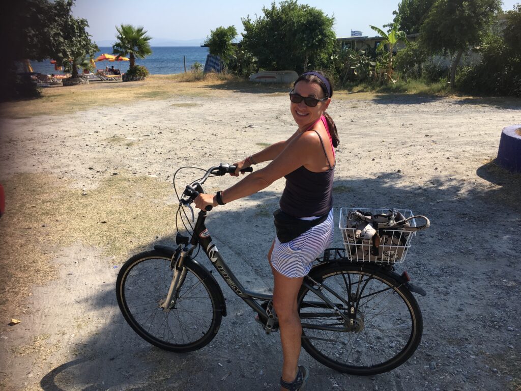 Woman is cycling on a Greek island near to the coast.