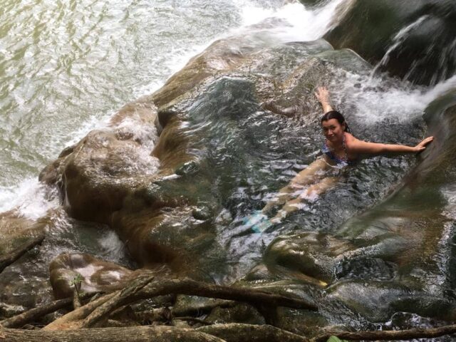 Woman is relaxing in warm waters on a rock in Thailand.