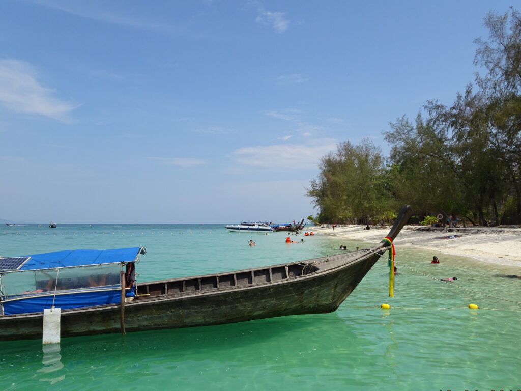 A boat sits in clear torquoise waters of Krabi.