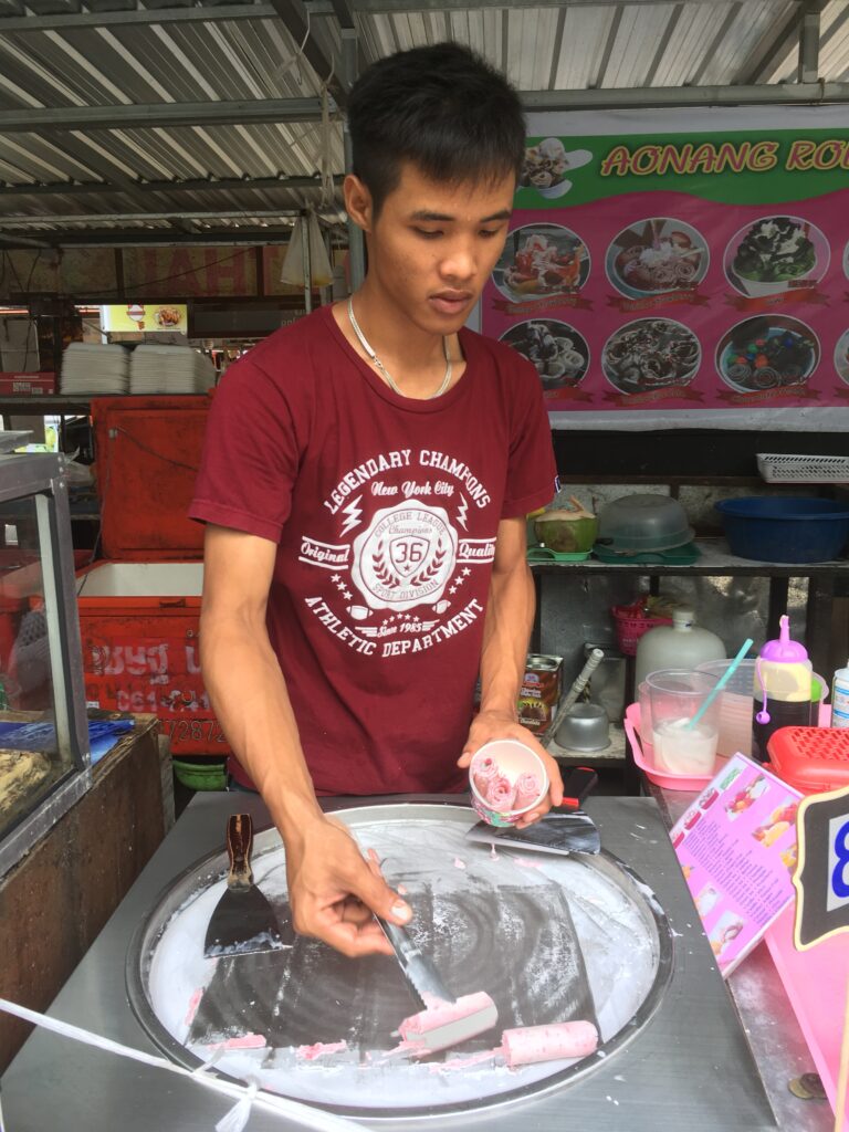 A Thai making local ice cream and rolling it to serve.